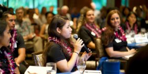 woman with lei speaking to group political science event