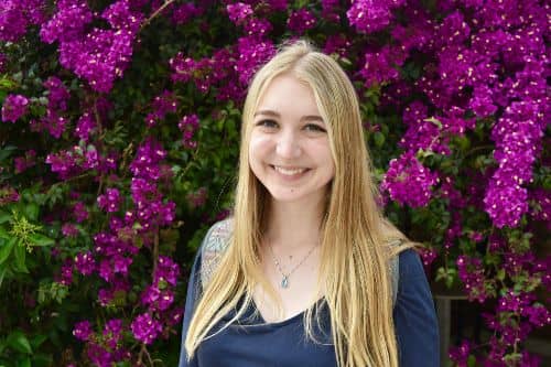 Emily Yerington, MAT '19, smiling at the camera with a floral background