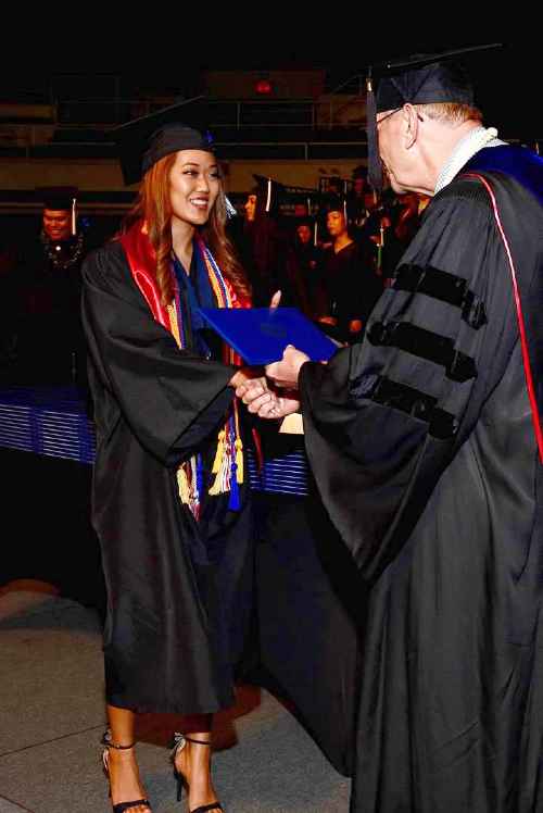 Meshelle Hirashima receiving her Chaminade diploma from Bro. Bernie Pleoger, SM