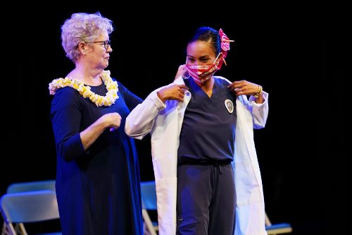 Nursing student putting on her white coat during the Nursing White Coat Ceremony
