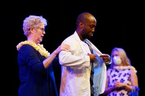Nursing student putting on his white coat during the Nursing White Coat Ceremony