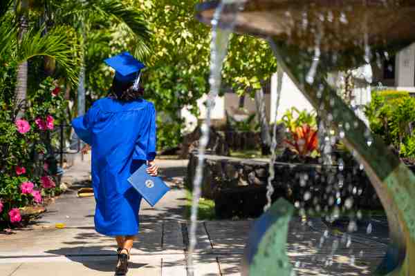 Chaminade student in blue regalia walking with her diploma