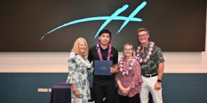 Chaminade President Dr. Lynn Babington, and Christine and Glenn Hogan congratulate Jacob Fernandez on his Aloha Spirit Award.