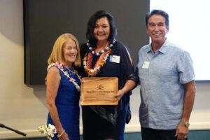Teri Chong '92 accepts her Hall of Fame award from Chaminade President Dr. Lynn Babington and Athletics Director Tom Buning.