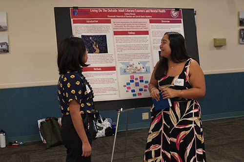 Lindsey Dimaya, left, a junior at Sacred Hearts Academy and a participant in Chaminade’s early college program, presented her findings to Joleigh Ballesteros-Magdaro.