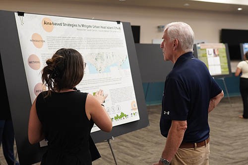 Sarah Carroll explains her research to Fr. Martin Solma during the Na Liko Na'auao Symposium.