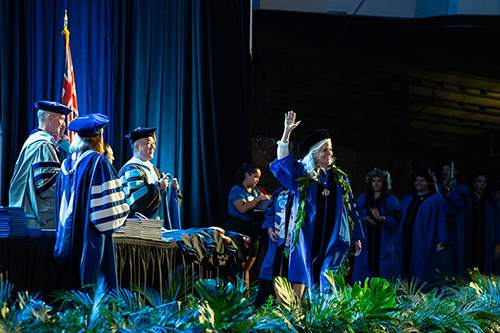 Commencement graduate student speaker Donna Kay Fisher waves at her fellow graduates before accepting her degree.