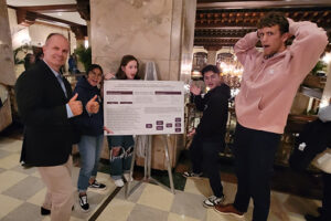 Dr. Eddie Merc gives two thumbs up after winning the Peregrine Best Practices Poster Competition. Students, from left, Kelsey Sablan, Liz Devine, Alexander Hernandez and Ross Reeves congratulated their professor.