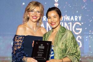 Lesley-Anne Leon Guerrero accepts The Institute for Extraordinary Banking’s Money Smarts Bank Award from Roxanne Emmerich, The Institute for Extraordinary Banking chair and founder.