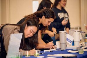 Recent 2024 alumna, from left, Haley Hayakawa and Naomi Noguchi sign up to win door prizes.