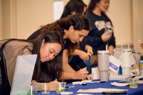 Recent 2024 alumna, from left, Haley Hayakawa and Naomi Noguchi sign up to win door prizes.
