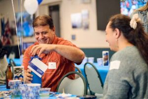 Dr. Sean Scanlan opens his gift with alumna Nicole Sagapolutele watching on.