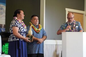 Chaminade School of Education and Behavioral Sciences Dean Dr. Dale Fryxell says a few congratulatory words to Sacred Hearts School Principal Tonata Lolesio after she received her Pineapple Award, as Llewellyn Young, Ph.D., superintendent of Hawaii Catholic Schools listened in.