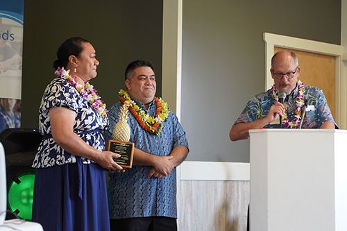 Chaminade School of Education and Behavioral Sciences Dean Dr. Dale Fryxell says a few congratulatory words to Sacred Hearts School Principal Tonata Lolesio after she received her Pineapple Award, as Llewellyn Young, Ph.D., superintendent of Hawaii Catholic Schools listened in.