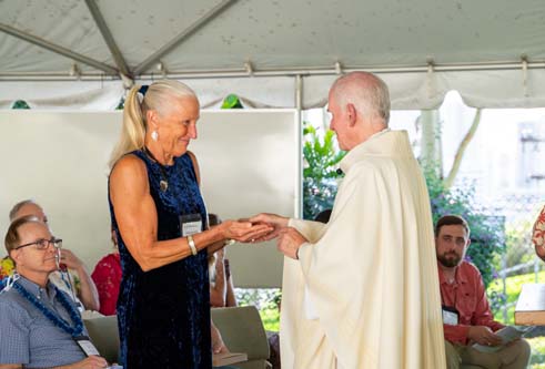 As part of the MEA Formation rituals, Fr. Martin Solma annoints the hands of Dr. Gail Grabowsky.