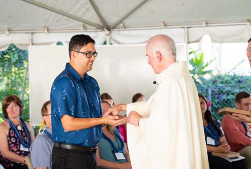 As part of the MEA Formation rituals, Fr. Martin Solma annoints the hands of Dr. Rylan Chong.