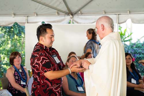 As part of the MEA Formation rituals, Fr. Martin Solma annoints the hands of Pono Riddle.
