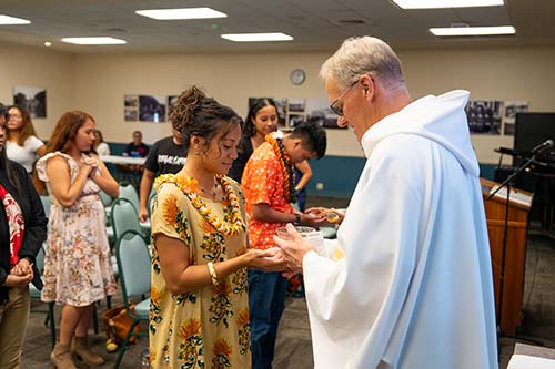 Nursing major Tia Kaʻiulani Tabisola ’25 has her hands anointed by Fr. Chris Wittmann during the St. Luke's Blessing of the Hands on October 16.